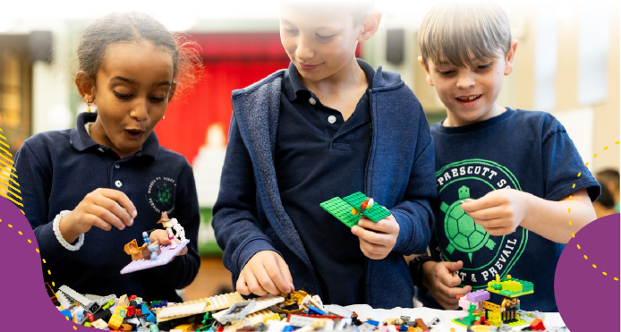 Photo of three children excitedly playing with LEGO bricks.